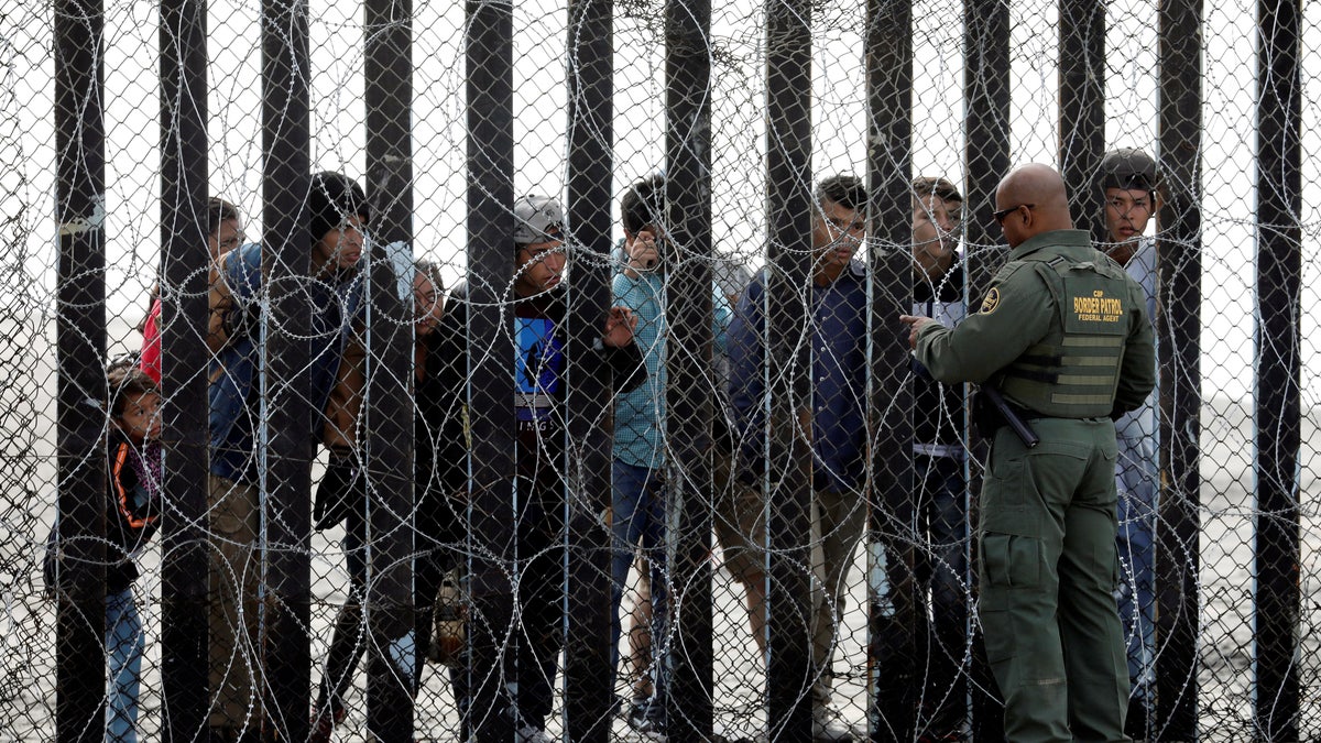 A U.S. Customs and Border Protection border patrol agent talks to people on the Mexican side of the border wall at Border Field State Park in San Diego, California, U.S., November 28, 2018. REUTERS/Chris Wattie