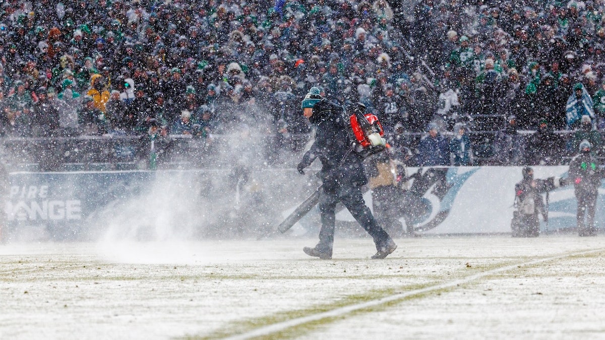 Grounds keepers run onto the field during the game with snowblowers to clear the lines in blizzard conditions during the NFC Divisional playoff between the Eagles and the Rams at Lincoln Financial Field on January 19, 2025 in Philadelphia, Pennsylvania.