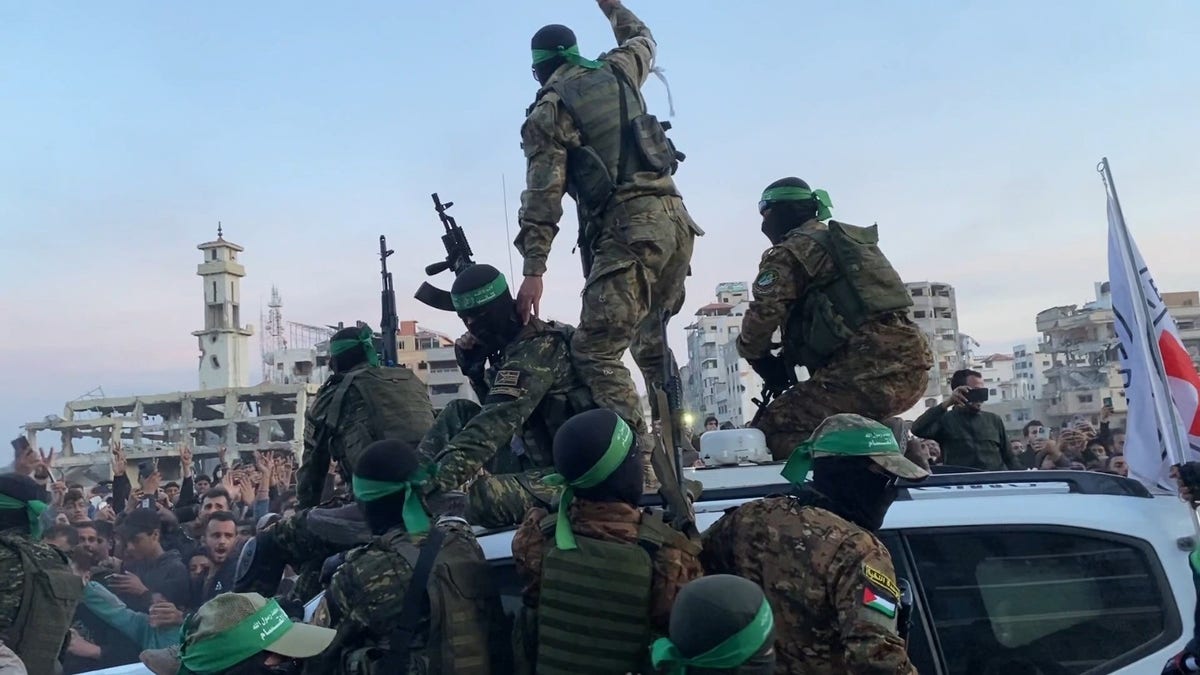 Hamas terrorists wave to Gazans during Sunday's release of three Israeli hostages.