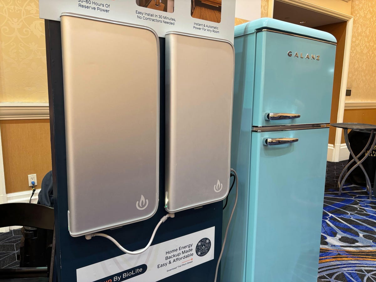 Two gray batteries with a blue refrigerator in the background.