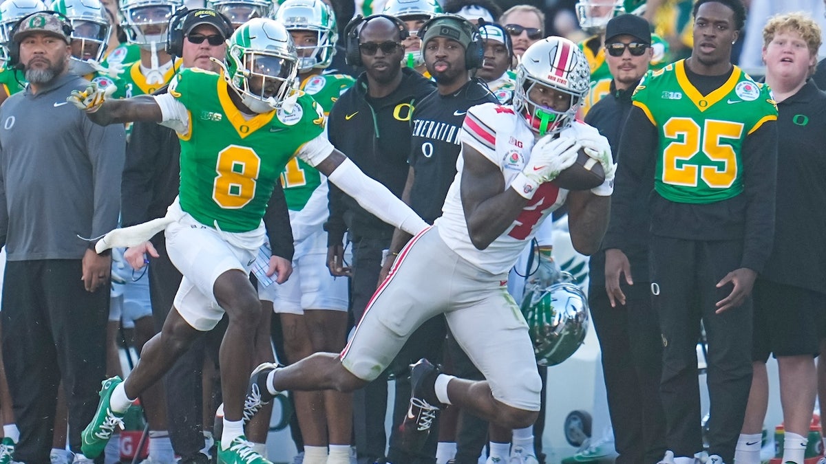 Ohio State Buckeyes wide receiver Jeremiah Smith (4) catches a pass in front of Oregon Ducks quarterback Dillon Gabriel (8) during the first half of the College Football Playoff quarterfinal at the Rose Bowl in Pasadena, Calif. on Jan. 1, 2025.