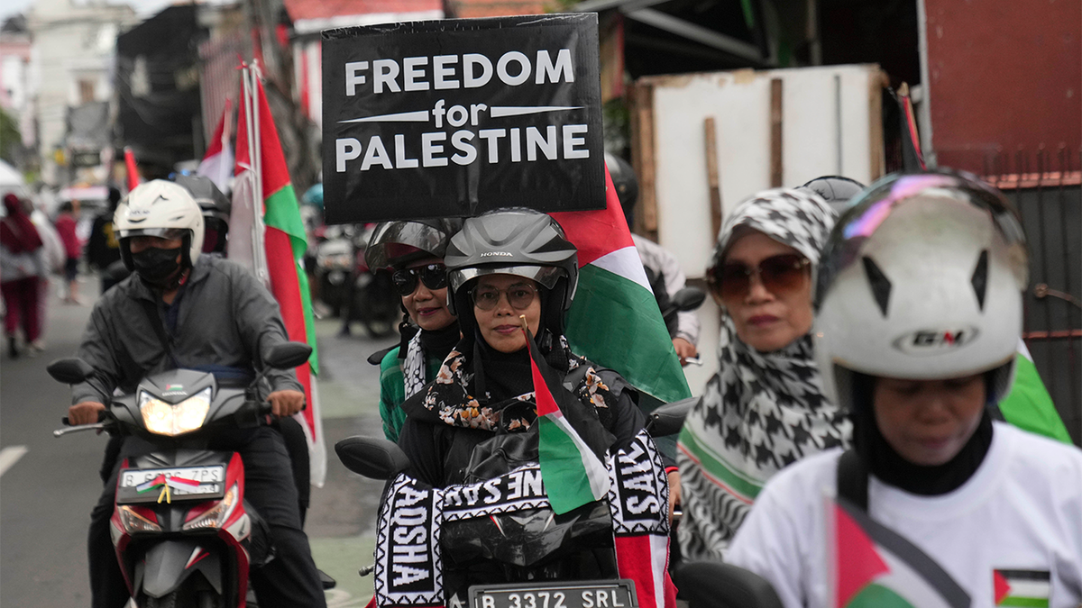 Muslim women display a poster as they ride motorcycles