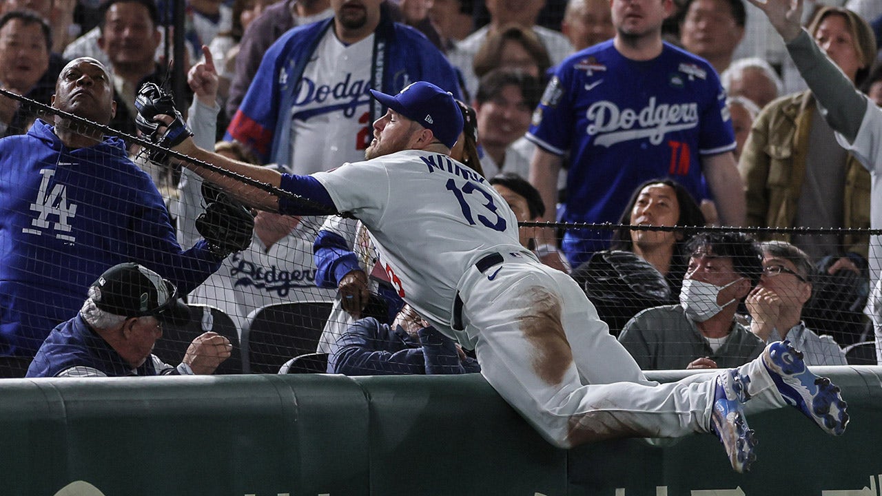 Dodgers’ Max Muncy looks stunned as ex-NFL quarterback Rodney Peete snags foul ball from the stands