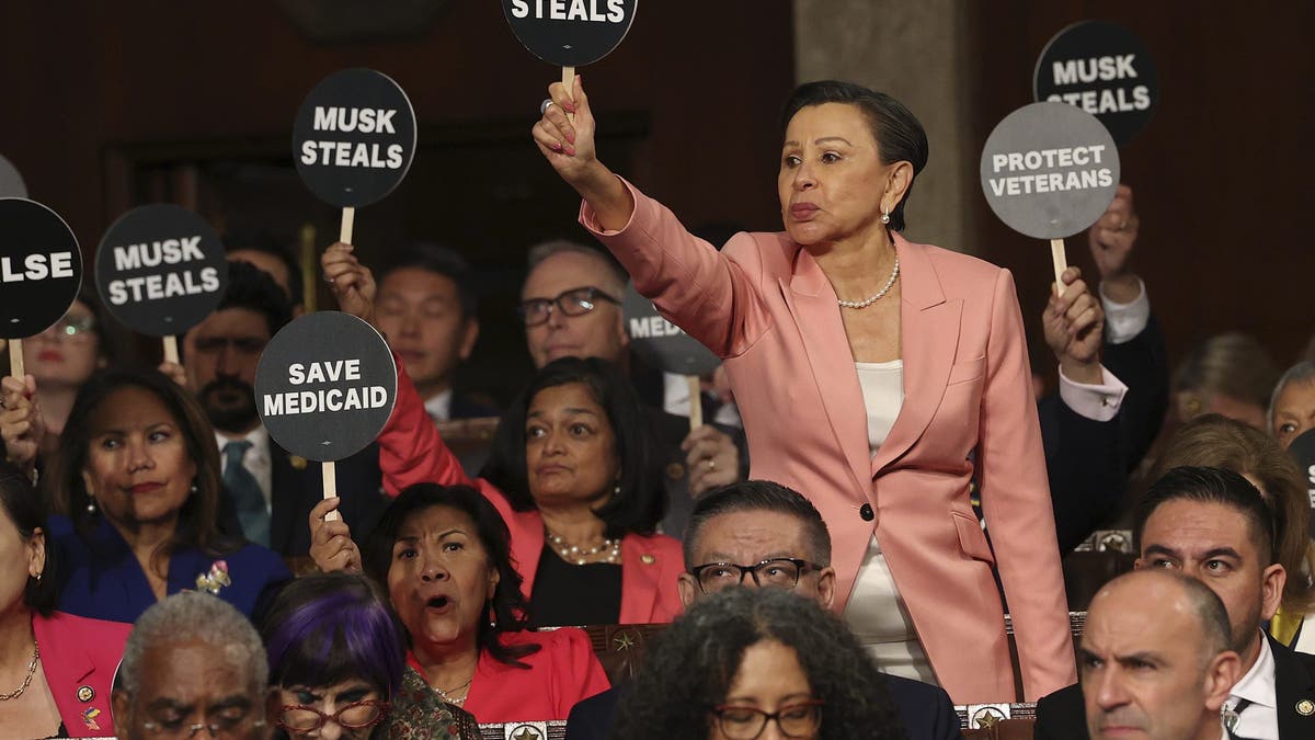 Rep. Nydia Velazquez, D-N.Y., holds a protest sign with fellow Democrats