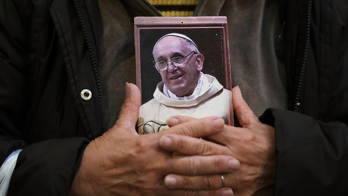 portrait of Pope Francis cradles in pilgrim's hands