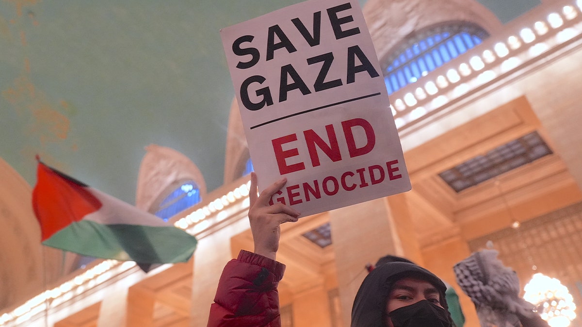Protester holds a sign that says "Save Gaza, End Genocide"