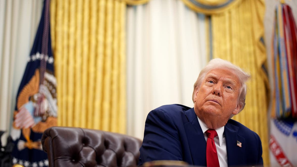 Trump at desk in Oval Office, photo looking up from floor perspective