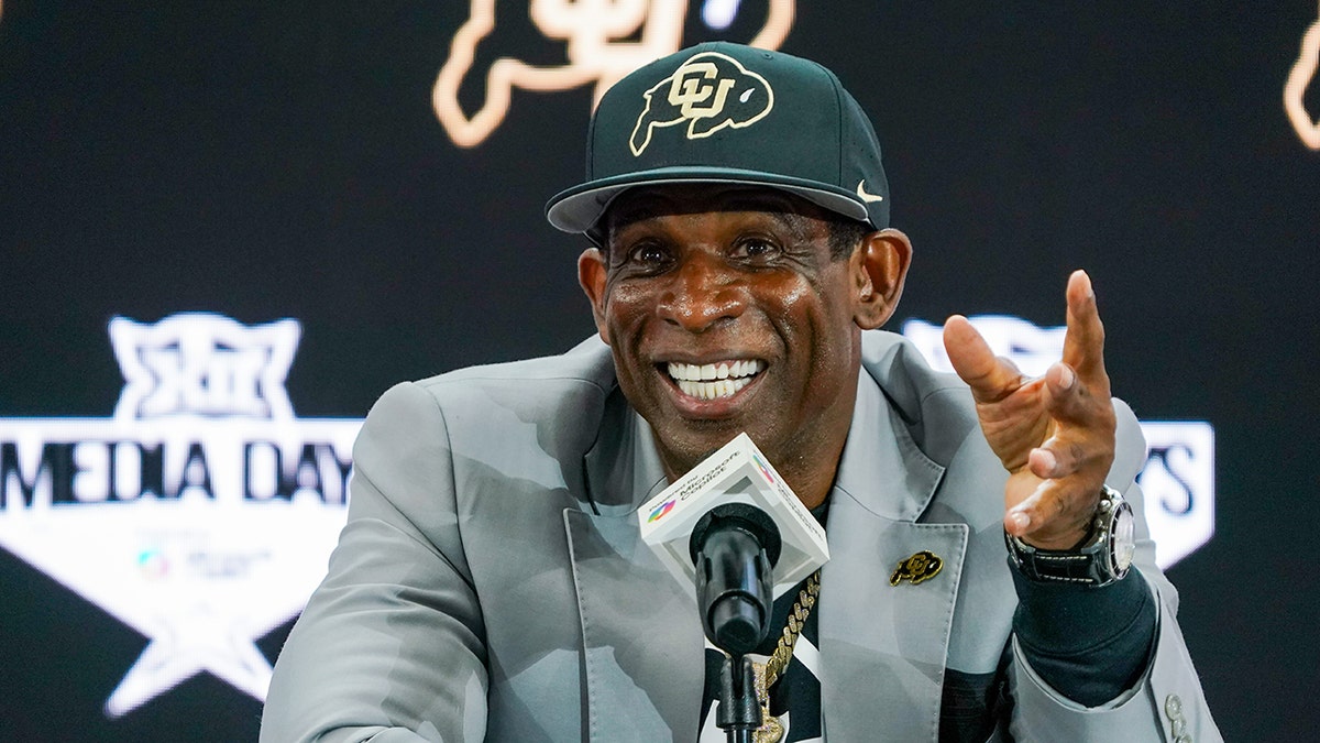 Deion Sanders smiles at microphone