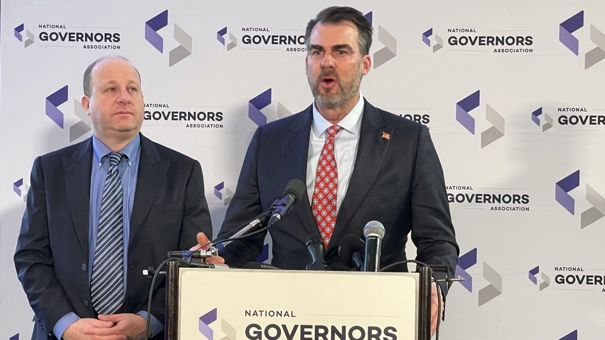 Gov. Stitt at podium with gov. polis to his right