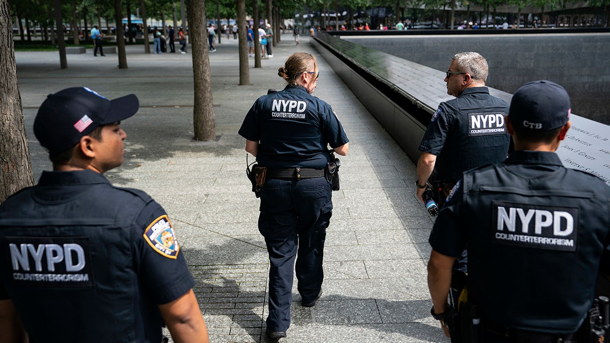 NYPD officer Michael Dougherty, a 25-year veteran, second from right, patrols with his colleagues beside the south reflecting pool of the 9/11 Memorial & Museum on Aug. 16, 2021, in New York.