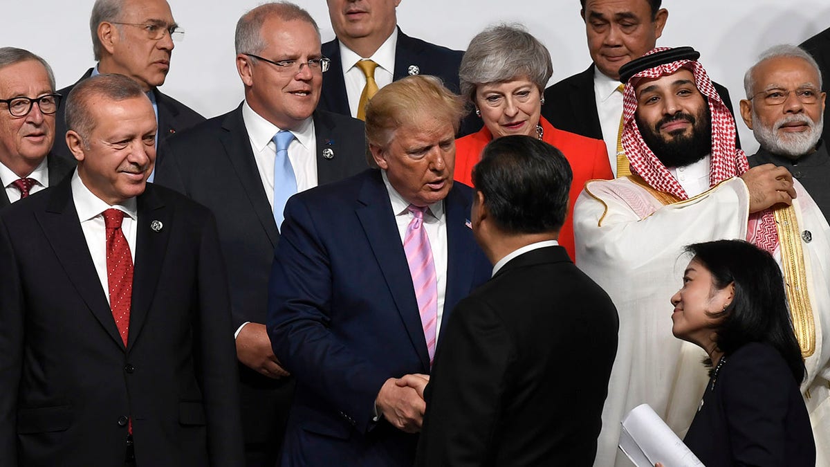 President Donald Trump, center, shakes hands with Chinese President Xi Jinping, as they gather for a group photo at the G-20 summit in Osaka, Japan, June 28, 2019.