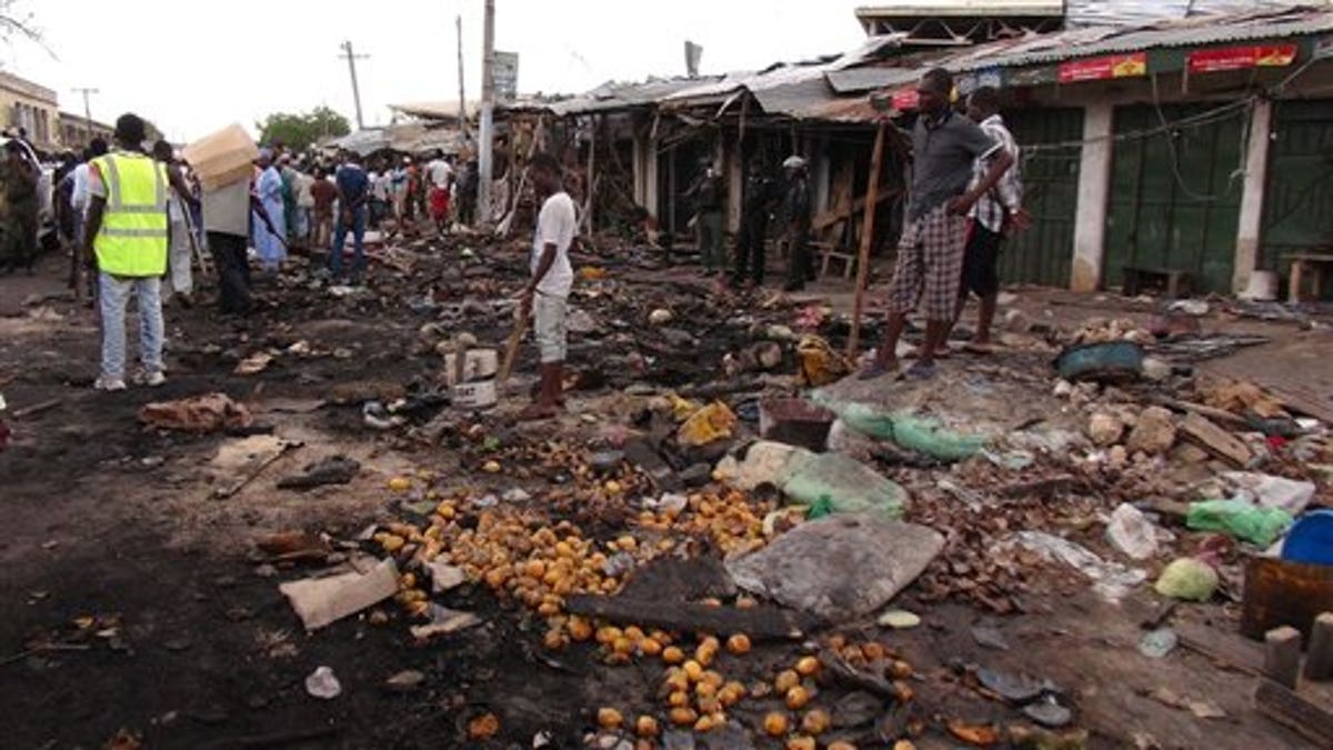 People gather at the scene of a car bomb explosion, at the central market, in Maiduguri, Nigeria, Wednesday, July 2, 2014. A car bomb in a marketplace in Maiduguri, the northeast Nigerian city that is the birthplace of Boko Haram extremism, killed at least 56 people on Tuesday, the leader of a civilian group that recovered the bodies said.Sadiq Abba Tijjani, leader of the Civilian Joint Task Force, told the Associated Press his group recovered at least 56 dead bodies at the blast site, mostly elderly women who sold peanuts and lemon juice at the market. ( AP Photo/Jossy Ola)