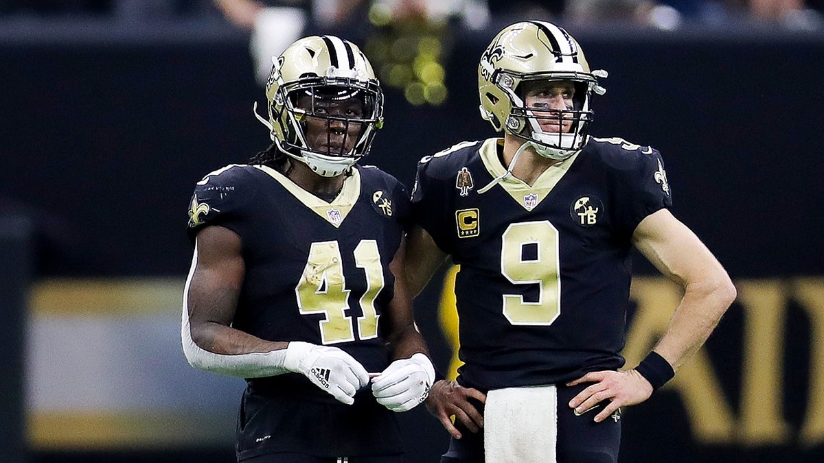 Alvin Kamara and Drew Brees look on field