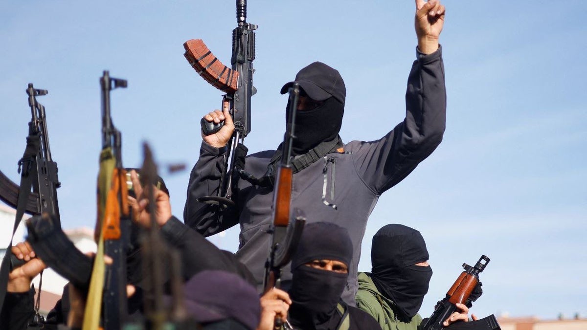 Terrorists with guns raised in the air.
