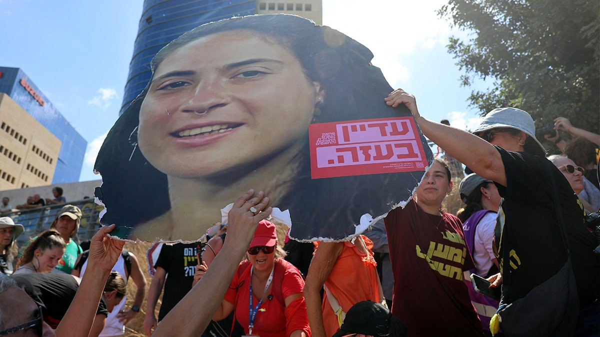 Protesters in Israel hold an enlarged image of deceased hostage Inbar Hayman's face