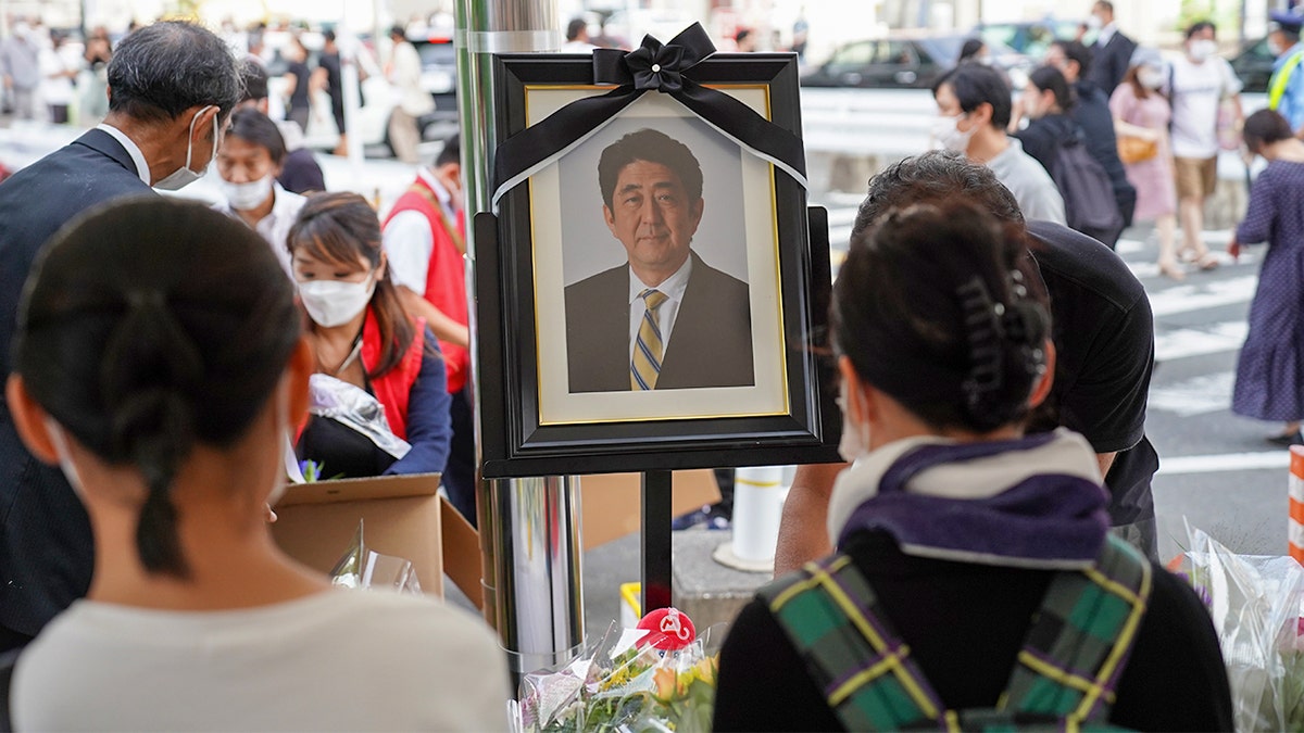 People look at an image of Shinzo Abe