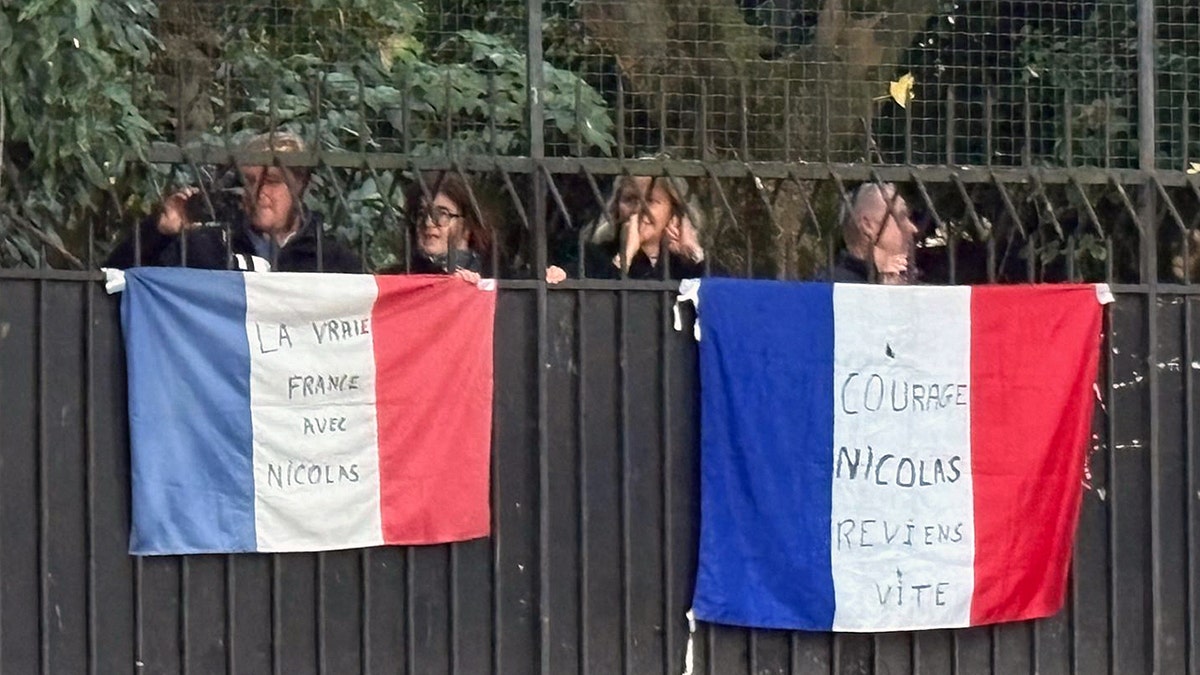 People with French flags over a fence