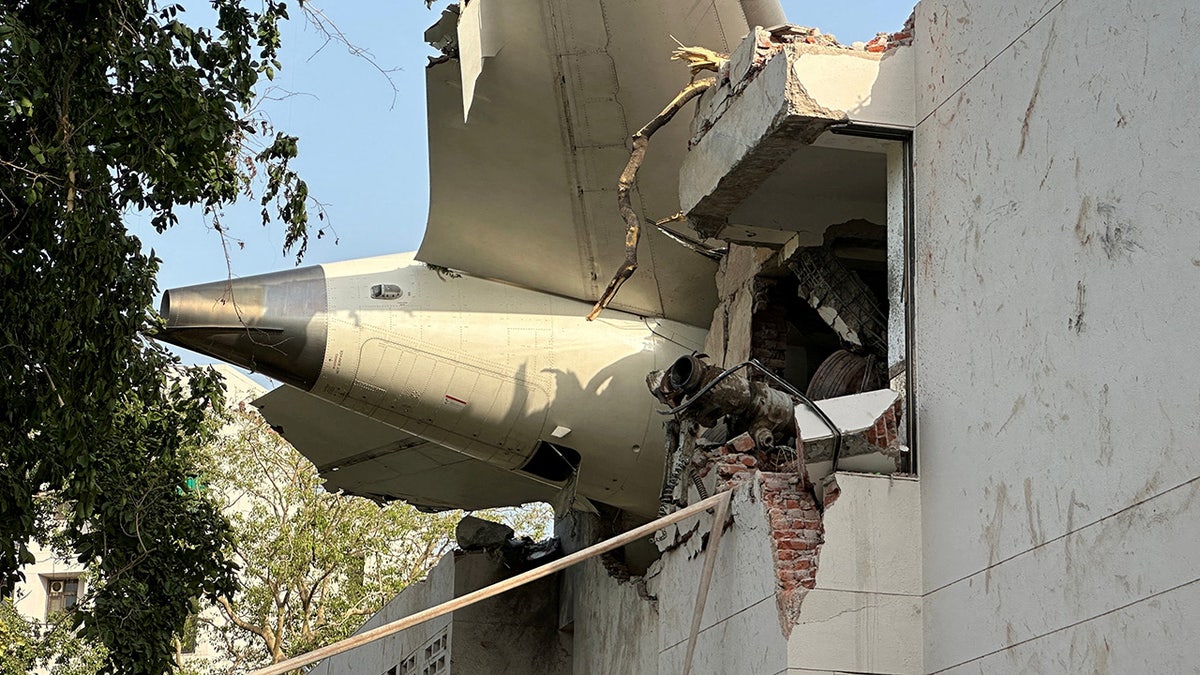 Tail of an Air India Boeing 787 Dreamliner stuck in building