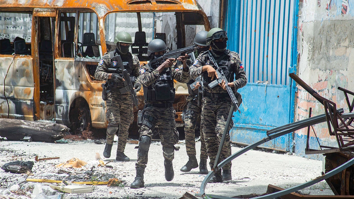 Police officers advance through a city street during a security operation in Port-au-Prince.