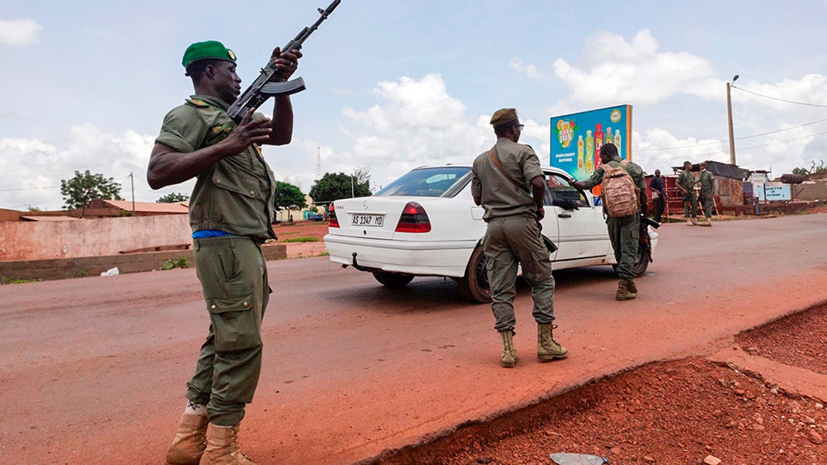 Malian soldiers check a vehicle in the garrison town of Kati, Mali, Tuesday Aug. 18, 2020. Malian soldiers took up arms and began detaining senior military officers in an apparent mutiny, raising fears of a potential coup after several months of anti-government demonstrations calling for the president's resignation. (AP Photo/Mohamed Salaha)