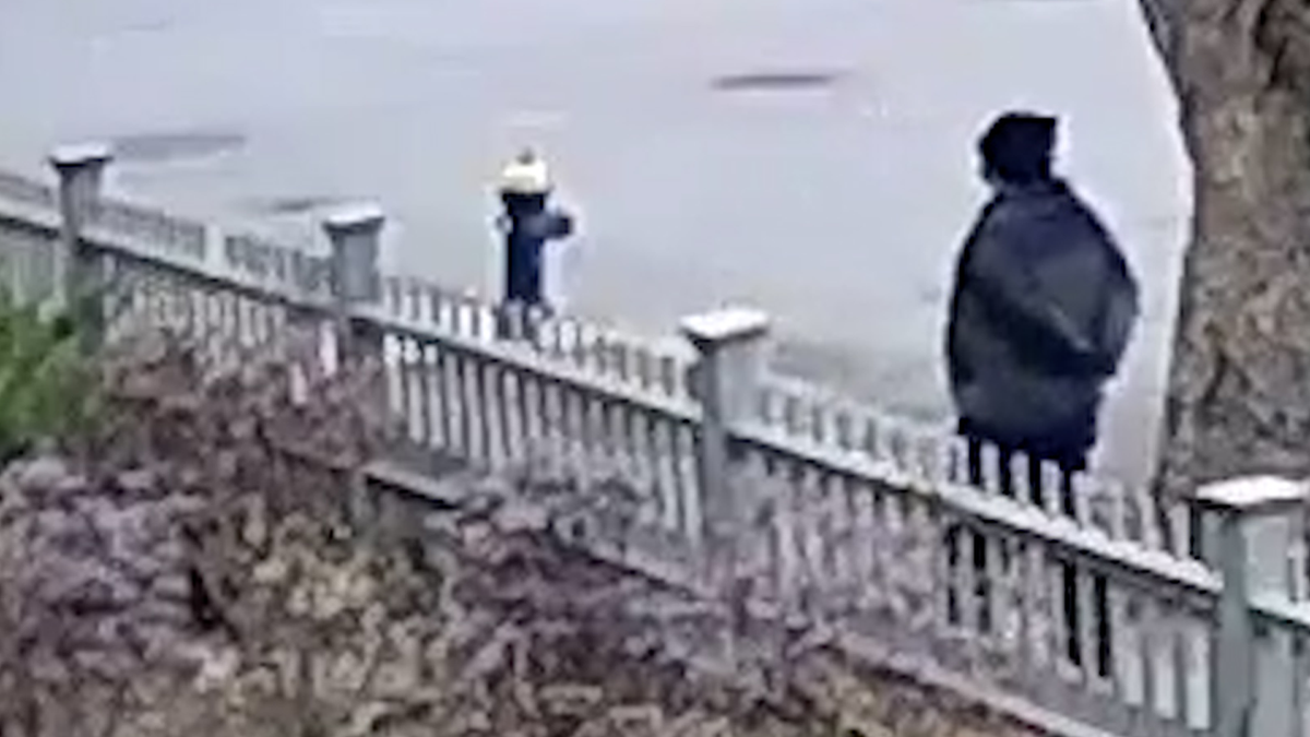 A still image from surveillance video shows the person of interest with his arms behind his back.