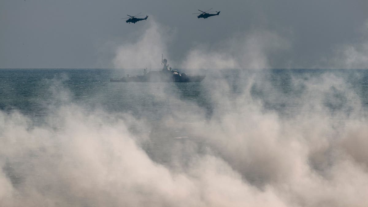 Russian army Mi-24 helicopters fly above a warship at the Turali range on the Caspian Sea coast in the Republic of Dagestan in Southern Russia on Sept. 23, 2020 during the "Caucasus-2020" military drills gathering China, Iran, Pakistan and Myanmar troops, along with ex-Soviet Armenia, Azerbaijan and Belarus.