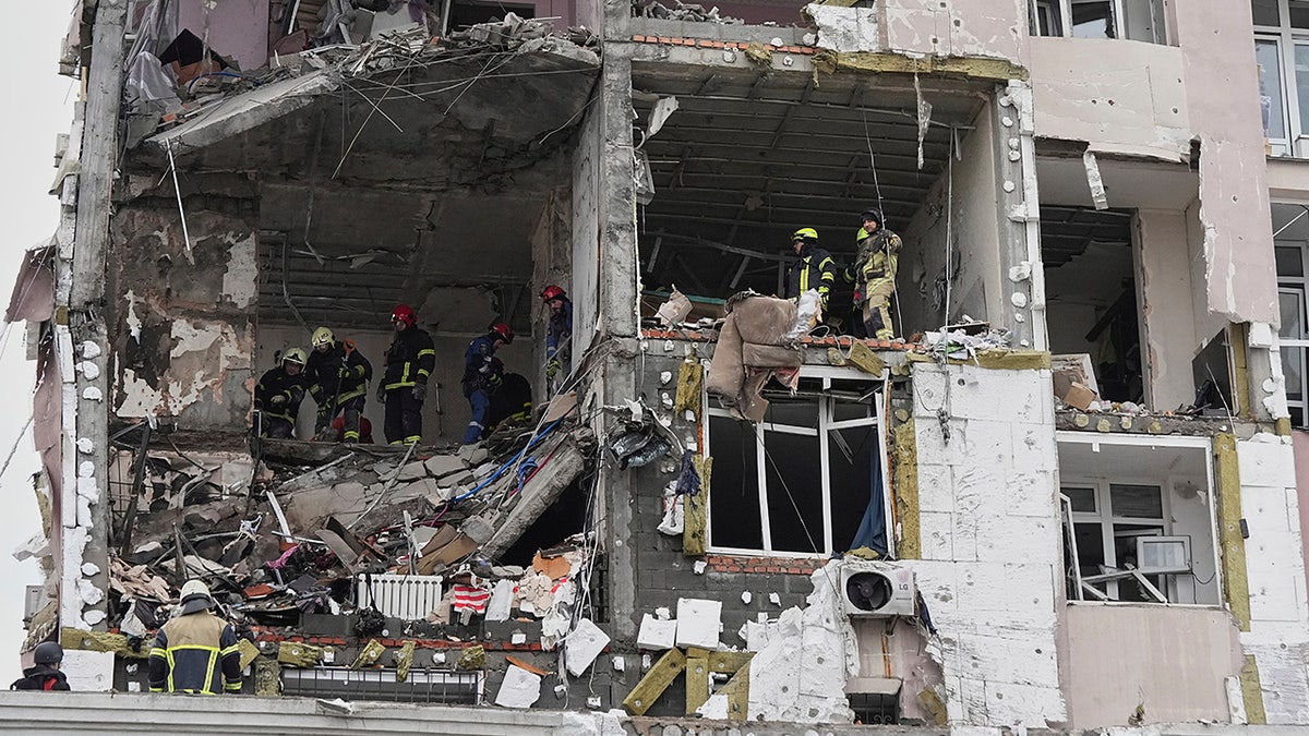 Rescuers look at debris inside apartment building damaged in Ukraine war