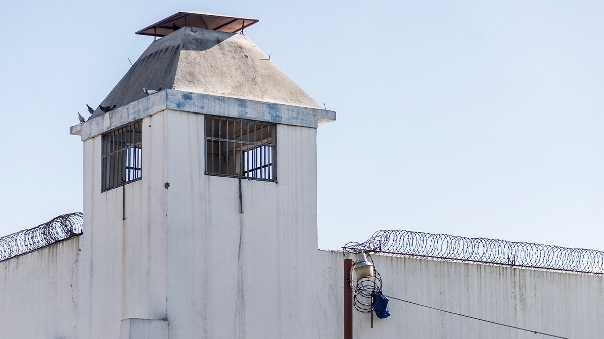 Prisoner clothing snagged on barbed wire outside a detention facility after a deadly escape.