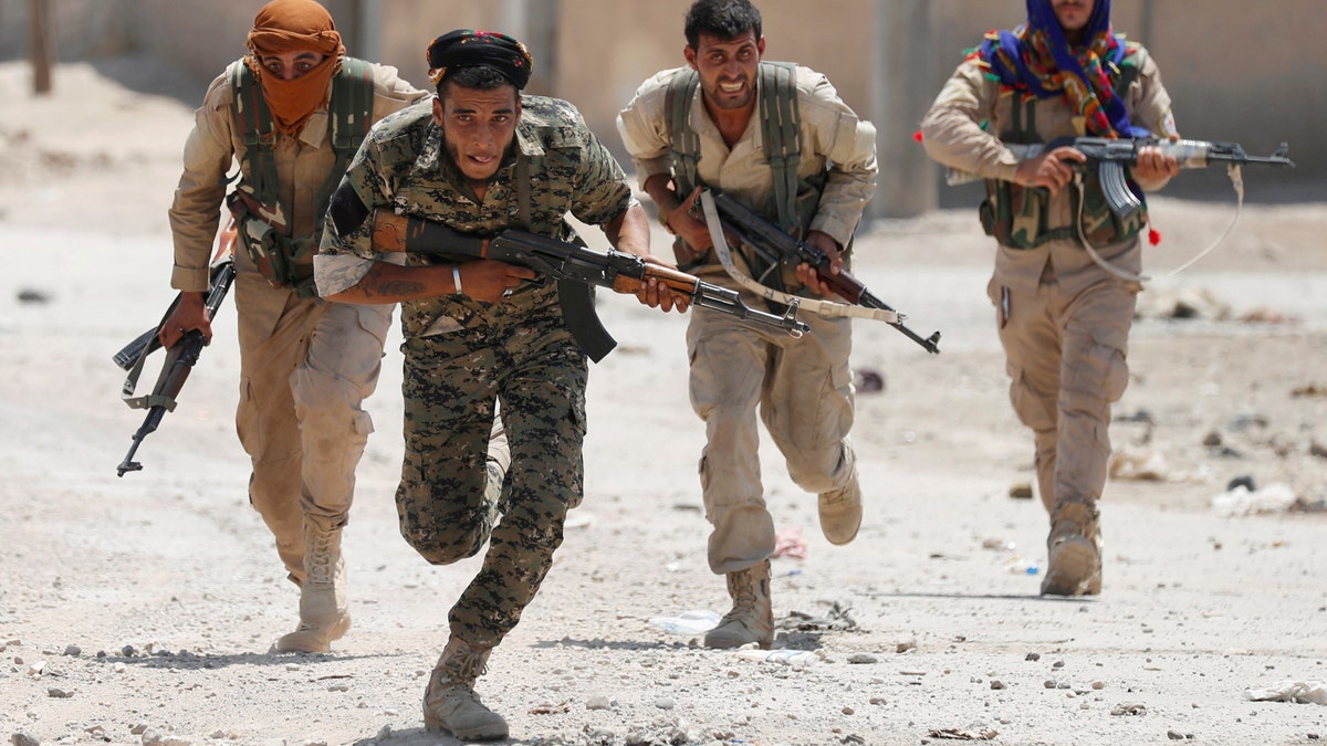 Kurdish fighters from the People's Protection Units (YPG) run across a street in Raqqa, Syria, July 3, 2017. Goran Tomasevic: "They were members of Kurdish YPG militia. They were running across the street because ISIS fighters' positions were nearby. I shot the picture in a last day of my assignment. I was lucky to have that picture as YPG fighters were giving very restricted access to media." REUTERS/ Goran Tomasevic/File Photo SEARCH "POY IS" FOR THIS STORY. SEARCH "REUTERS POY" FOR ALL BEST OF 2017 PACKAGES. TPX IMAGES OF THE DAY - RC164AFF4C20