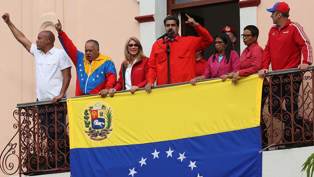 maduro speaking with massive venezuelan flag hanging at balcony