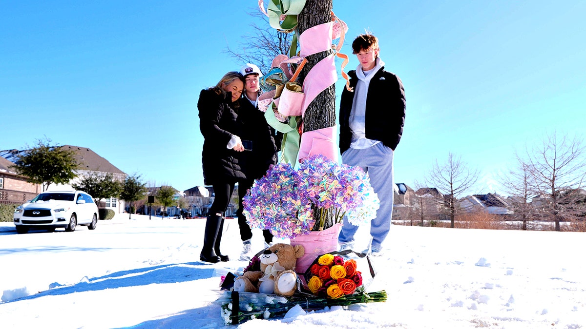 people standing around makeshift memorial