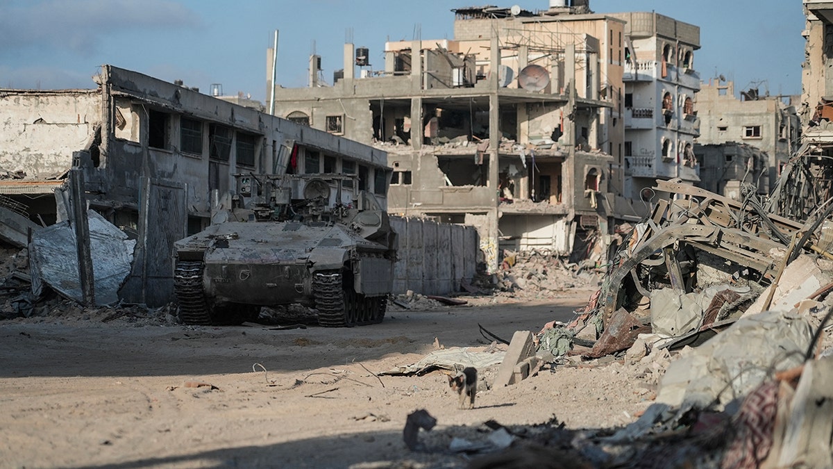 IDF soldiers in vehicle drive past destroyed buildings in Gaza