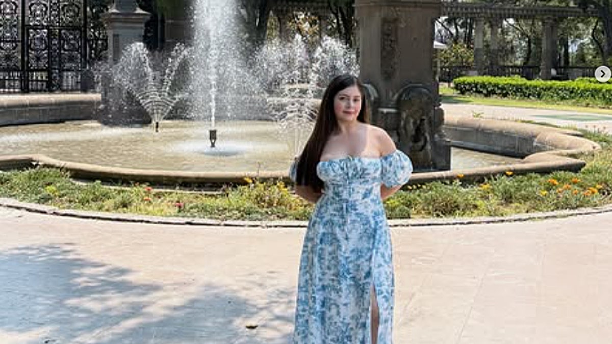 woman in blue sundress in front of fountain