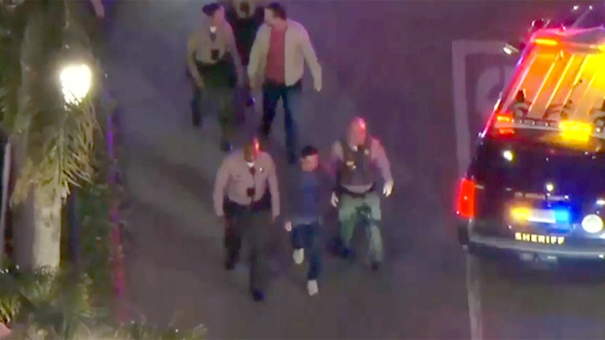 Officers escort two people outside of a restaurant in California.