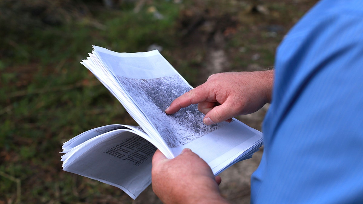 A man pointing at a crime scene photo.