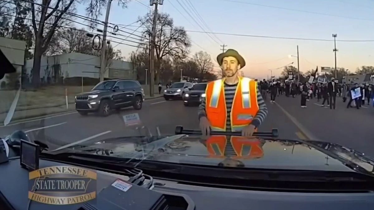 Protester holding onto car's push bar.