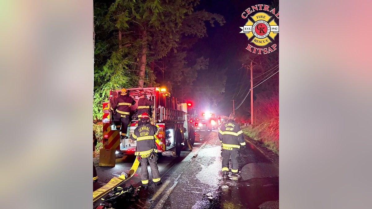 firefighters and fire trucks in the street at night