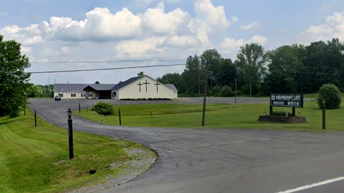 Abundant Life Fellowship church building and its roadside sign along an asphalt driveway.