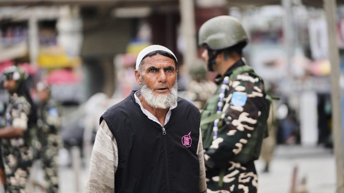 Indian soldiers stand guard as a Kashmiri Muslim man walks by, in Srinagar, Indian-controlled Kashmir, Friday, May 9, 2025.