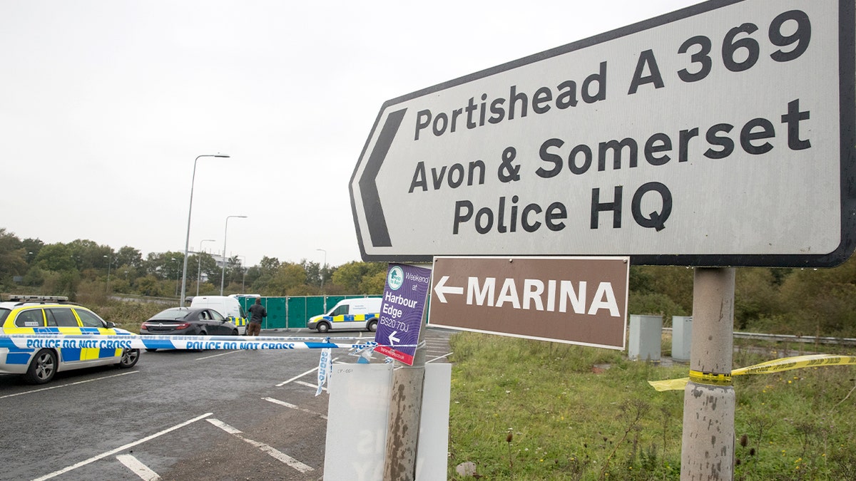 Armed officers and forensic personnel work along a cordoned-off roadside near a motorway junction following a fatal confrontation involving law enforcement.