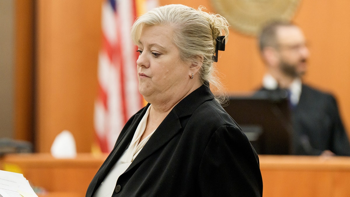 Kathy Nester walking across a courtroom toward a table.