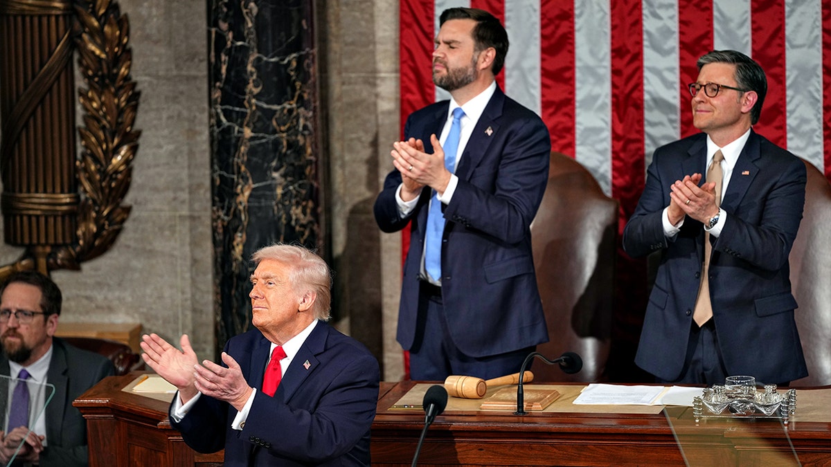President Donald Trump applauds with Vice President JD Vance and House Speaker Mike Johnson