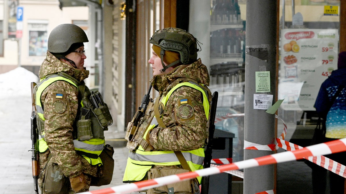 Ukrainian police officers cordon off a street near damaged storefronts after a deadly nighttime blast in Lviv.
