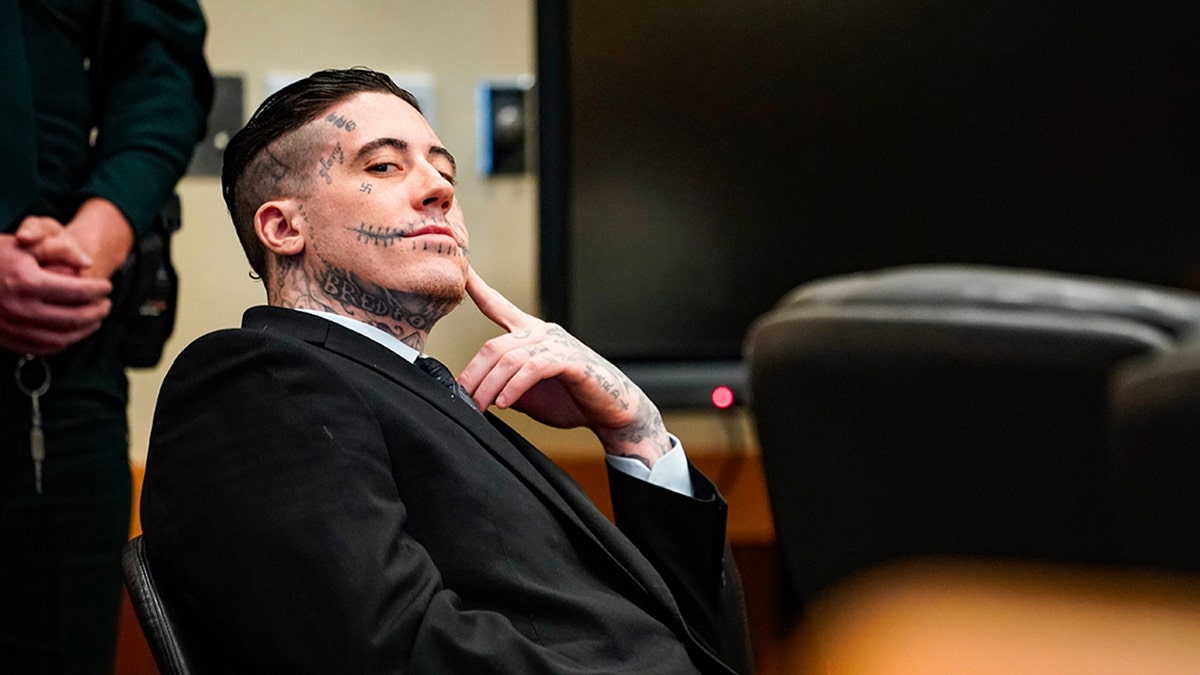 Wade Wilson in a dark suit sitting in court.