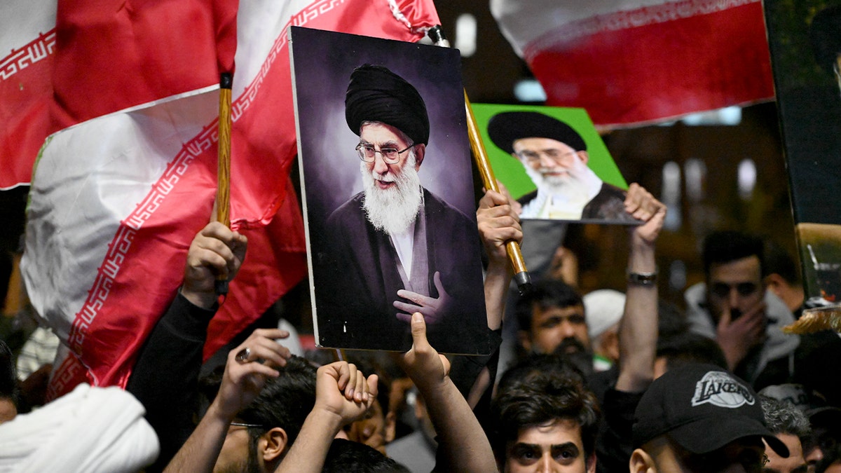 Protesters wave Iranian and Iraqi Hezbollah flags and hold portraits during a rally in Basra.