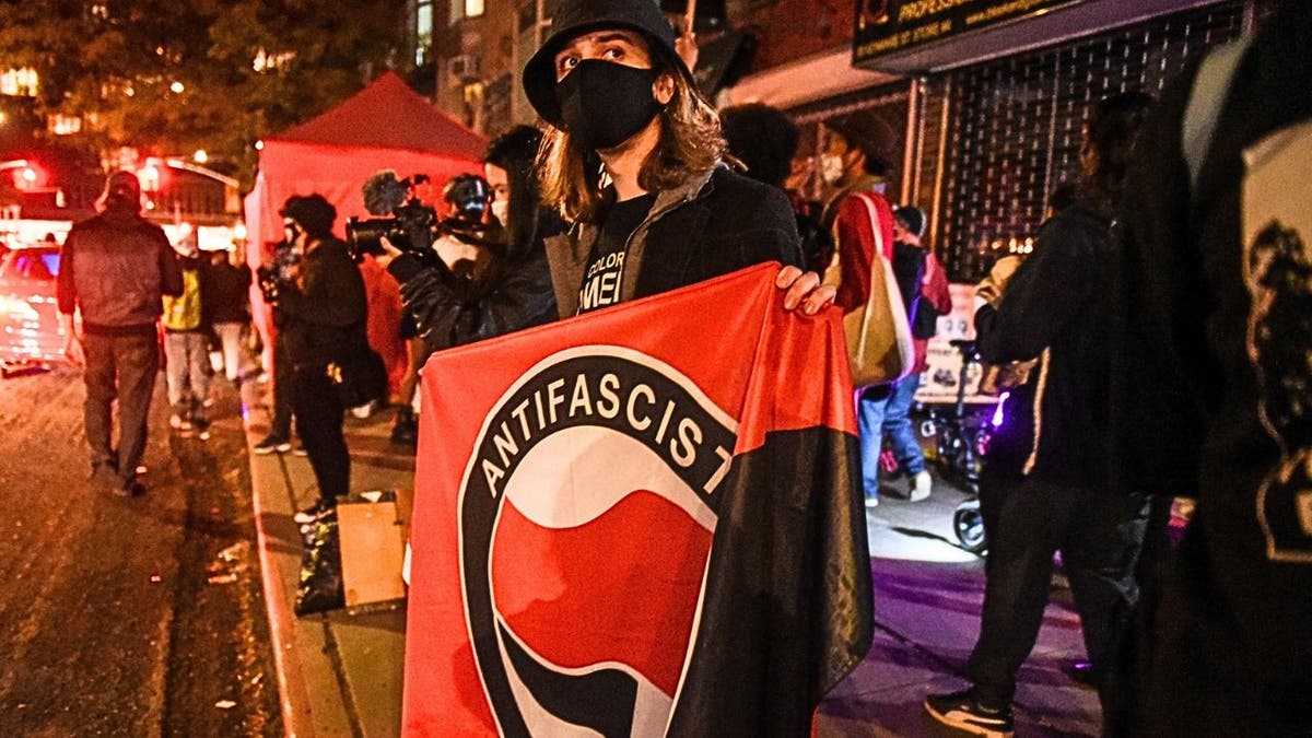 Masked protester holding Antifa banner during New York City protest at night