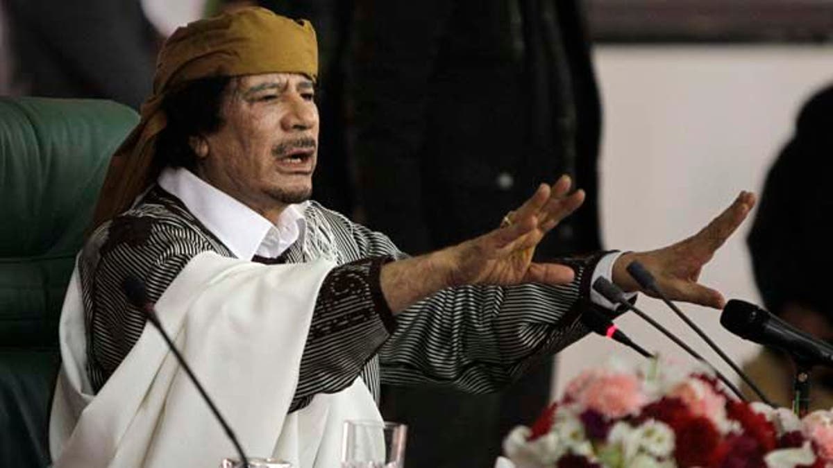 FILE - In this March 2, 2011 file photo, Libyan Leader Moammar Gadhafi gestures to supporters as he speaks in Tripoli, Libya. As rebels swarmed into Tripoli late Sunday, Aug. 21, 2011, and Gadhafi's son and one-time heir apparent Seif al-Islam was arrested, Gadhafi's rule was all but over, even though some loyalists continued to resist. (AP Photo/Ben Curtis, File)