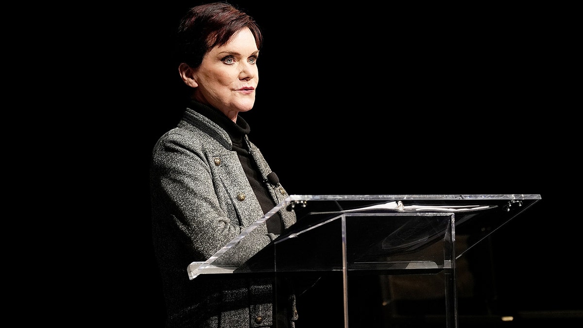 Candice DeLong at a podium speaking.