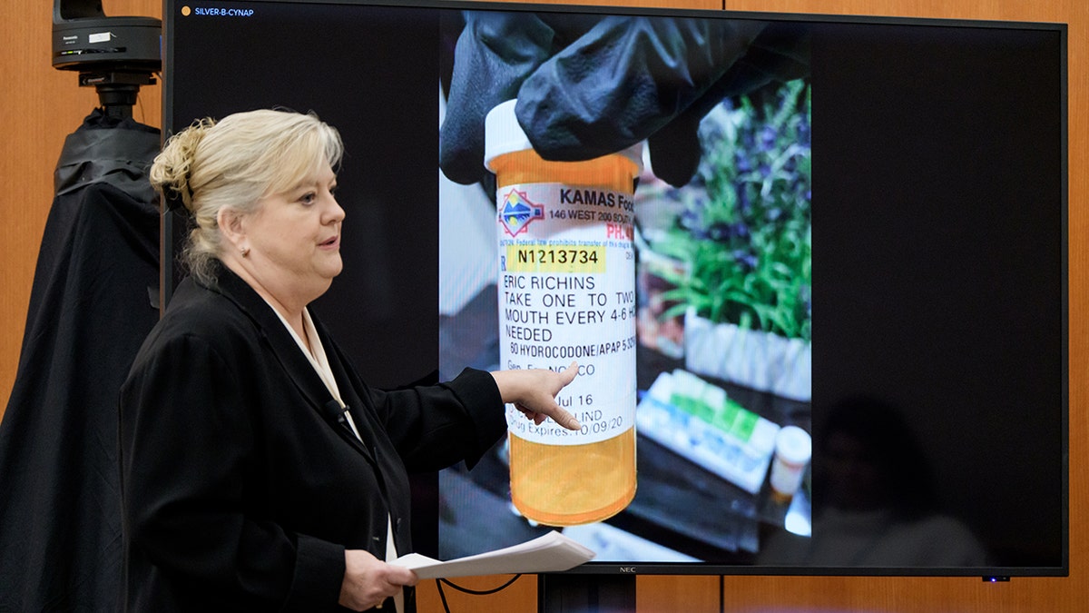 Kathy Nester stand before an image of a pill bottle while addressing a jury in a courtroom.