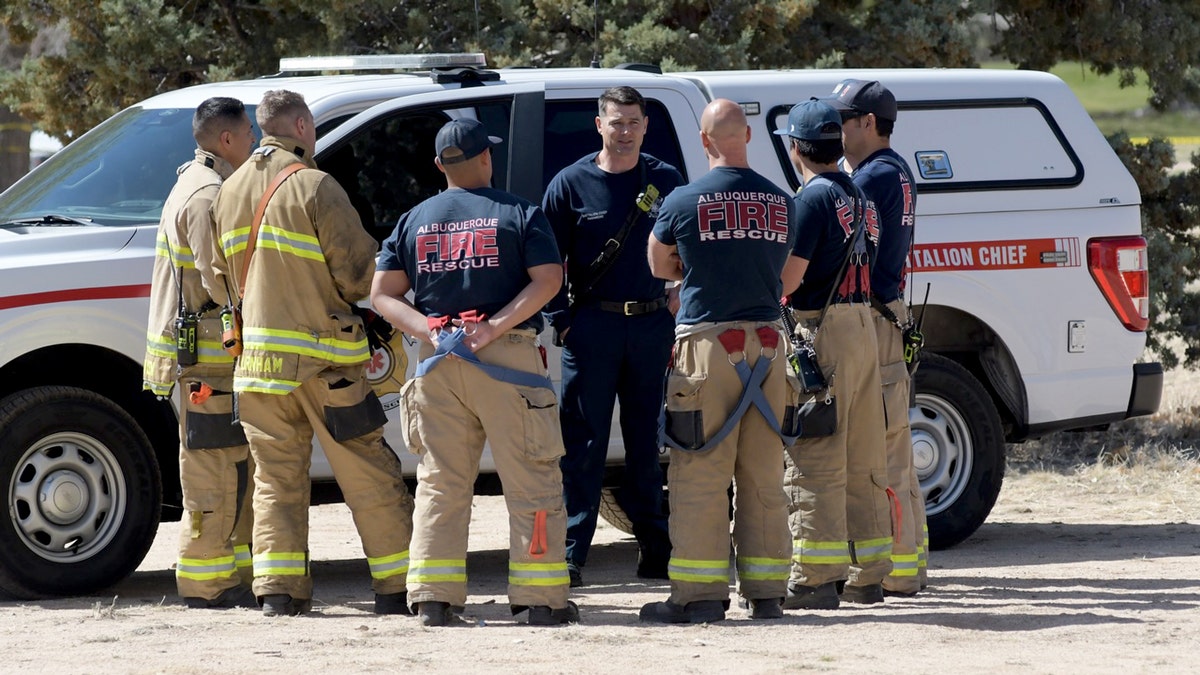 Albuquerque firefighters standing in a circle by a emergency vehicle